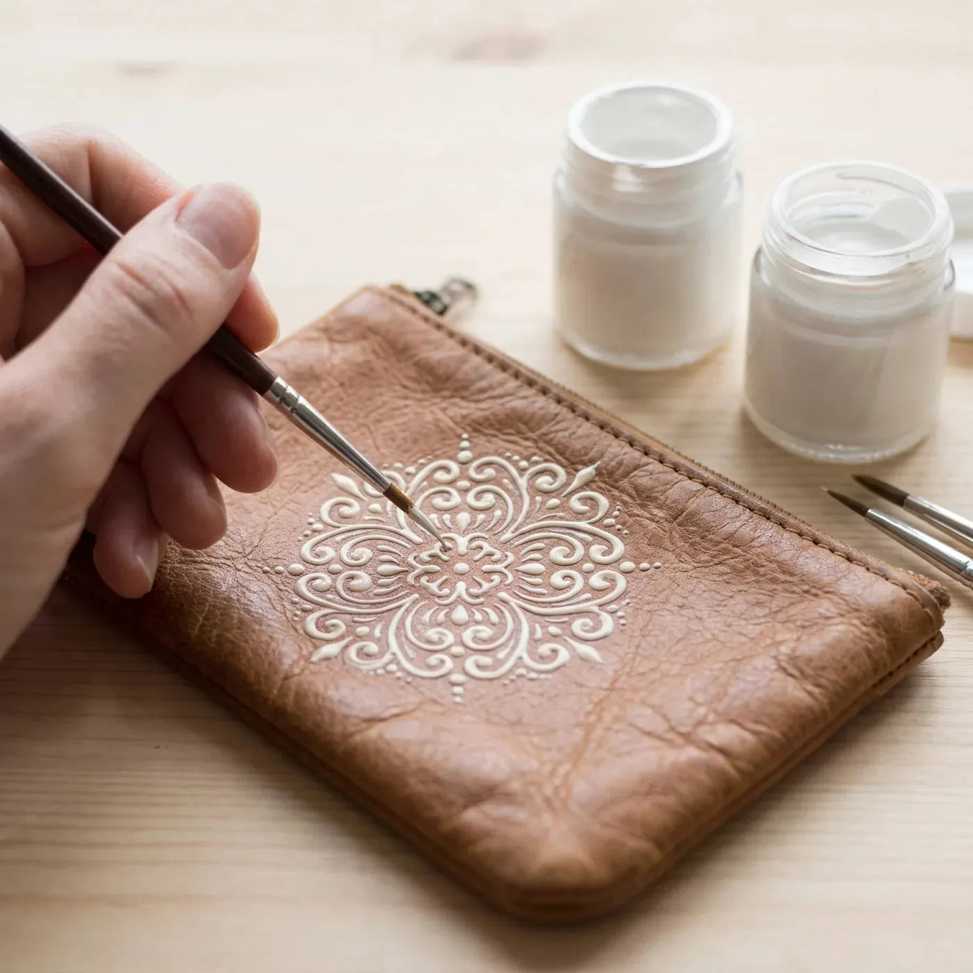 Jednofarebný ornament maľovaný farbou na textil na koženej peňaženke